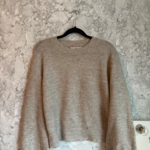 Beige stickad tröja - Mysig beige stickad tröja med rund hals och långa ärmar. Perfekt för kyligare dagar och enkel att matcha med olika outfits.