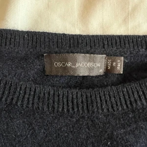 Mörkblå tröja från Oscar Jacobson - Säljer en stilren mörkblå tröja från Oscar Jacobson. Tröjan har en klassisk design med rund hals och långa ärmar. Perfekt för en elegant och avslappnad look.