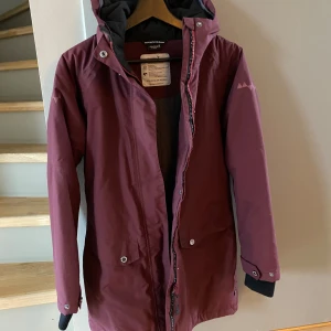 Vinröd jacka från Isbjörn of Sweden - Vinröd vinterfodrad jacka från Isbjörn of Sweden. Materialet är vattentätt och andas. Enligt lapp i jackan är den barnstorlek 146/152 men den känns mycket större, mer som 158/164 eller XXS damstorlek. Jackan är endast provad men var för stor och har bara hängt i garderoben så är i nyskick! Nypris ca 1600kr. 