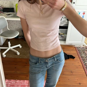 Ljusrosa croppad t-shirt från Gina Tricot - Säljer en ljusrosa croppad t-shirt från Gina Tricot. Den har en enkel design med korta ärmar och rund halsringning. Perfekt för en avslappnad stil.