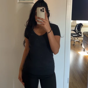 Svart t-shirt från Tommy Hilfiger - Säljer en klassisk svart t-shirt från Tommy Hilfiger med v-ringning och korta ärmar. Perfekt basplagg för alla tillfällen. Liten logga på bröstet ger en stilren touch. Storlek xxs men passar mig med xs. 