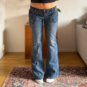 Lågmidjade vintage jeans  - Så coola lågmidjade vintage jeans med bootcut. Snygga detaljer på fickorna. Midjemåttet är ca 43cm rakt över och innerbenslängden är ca 78cm.