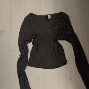 Grå långärmad topp från Hm - Säljer en stilren grå långärmad topp från Divided. Toppen har en söt rosett och spetsdetaljer vid halsringningen 💕