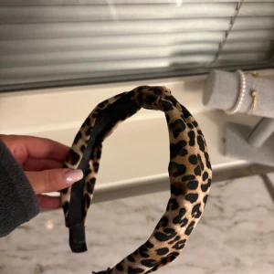 Leopardmönstrat diadem - Snyggt diadem med leopardmönster i bruna och svarta nyanser. Perfekt för att ge en trendig touch till din outfit. 