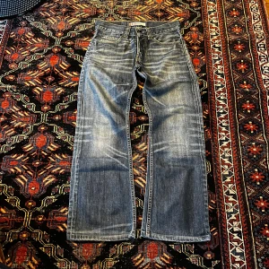 Gråblå bootcut från Levi's - Snygga grå jeansbyxor från Levi's med klassisk femficksdesign och en bootcut passform (512). Byxorna har en diskret tvättad look och är perfekta för en avslappnad stil. Bara att skriva vid frågor.