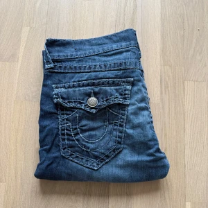 True religion jeans - Säljer dessa true religion jeans då passformen itne passar mig direkt, köpta i andrahand. jeansen har broderade detaljer på bakfickorna och en klassisk femficksdesign. De har en rak passform och är perfekta för en avslappnad stil. Knapp och dragkedja framtill. En av knapparna däbaka är bytta (se bild 4) Om du har några frågor eller vill ha mer bilder så är det bara att höra av dig 🌟tar emot bud 🤩