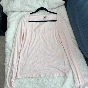 Ljusrosa långärmad topp från Nelly - Säljer en söt ljusrosa långärmad topp från Nelly. Toppen har en v-ringad design med spetsdetaljer längs halsringningen. Perfekt för en avslappnad stil. Så fin verkligen! Har inte använts💕🌸💕💕💖