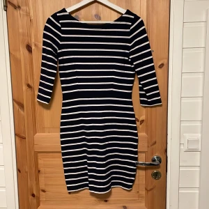 Randig klänning från Boomerang - Säljer en stilren randig klänning från Boomerang i marinblått och vitt. Klänningen har trekvartsärmar och en figurnära passform som ger en klassisk look. Perfekt för en avslappnad men ändå elegant stil.