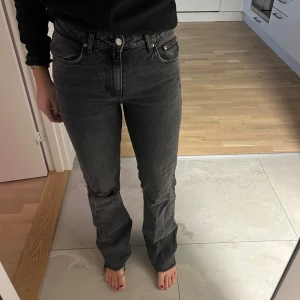 Grå jeans med slitningar - Snygga grå jeans med slitningar på ena knät och slitningar längst ner. De har en klassisk femficksdesign och en knappgylf. 