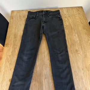 Svarta jeans från Replay - Helt nya svarta Replay Anbass jeans i slim fit. De har en klassisk femficksdesign med knapp och dragkedja. Perfekta för en stilren look.