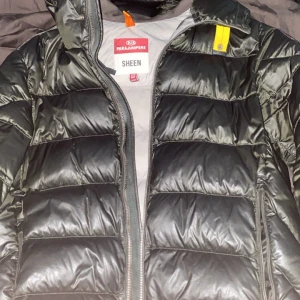 Svart dunjacka från Parajumpers - Säljer en snygg svart dunjacka från Parajumpers, modell Sheen. Jackan har en quiltad design med dragkedja framtill och en cool patch på ärmen. Perfekt för kyliga dagar med sin varma och stilrena look. 🖤