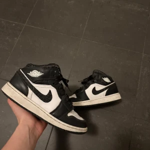 Nike Air Jordans 1s MID   - Snygga Nike Air Jordans i klassisk svart och vit färgkombination. Skorna har en ikonisk design med snörning och den välkända Nike-loggan på sidan. Perfekta för dig som vill ha en stilren look. Köpta på foot locker för 1500kr, såklart äkta stilrena fint sick har en liten skada uppe i sulan men sysn inte när skon är på, är det några frågor är det Bara att komma i dm 🔥✅💯