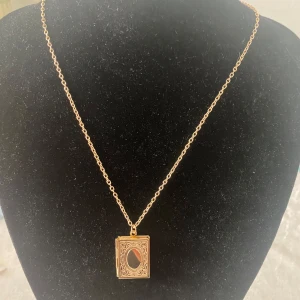 Magisk Bok  / Fotoram Halsband  - Elegant guldigt halsband med en rektangulär medaljong som kan öppnas. Medaljongen har ett intrikat mönster på framsidan och plats för ett foto inuti. Perfekt för att bära nära hjärtat. Helt ny , färg kvar silver, gul och ros guld 