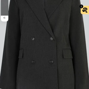 Mörkgrå oversized kostymkavaj - Snygg mörkgrå dubbelknäppt kavaj med klassisk krage och raka axlar. Kavajen har en oversized passform, fyra knappar framtill och fickor med lock. Perfekt för dig som gillar en stilren och modern look. Aldrig använd prislapp kvar 