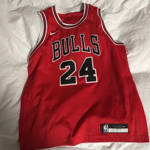 Chicago Bulls X Nike - Säljer ett par röda Chicago Bulls basketshorts och basketlinne från Nike med vita och svarta detaljer, shortsen har elastisk midja och broderad Bulls-logga på benen. Perfekta för basket eller streetwear, med klassisk NBA-stil och bekvämt material. Storlek 14-16 år på linnet samt 12-14 år på shortsen