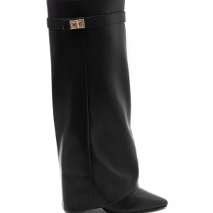 Svarta stövlar med spetsig tå - Stilrena svarta stövlar i skinn med spetsig tå och dekorativt spänne upptill. Klassisk och tidlös design med hög skaft och platt sula, perfekt för att lyfta vilken outfit som helst. 