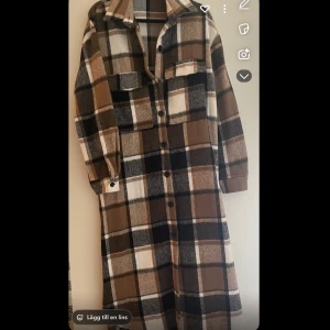 Rutig skjortklänning från ChicMe - Snygg lång skjortklänning från ChicMe i brunt, svart, beige och vitt rutmönster. Klänningen har långa ärmar, krage, knappar hela vägen och två bröstfickor. Perfekt för lager-på-lager och chill höststil.