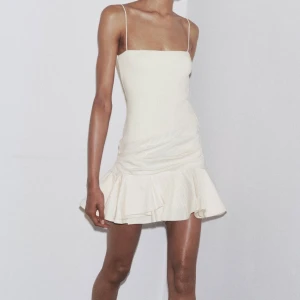 Ljus kort klänning med volang - Supersöt ljus kort klänning med smala axelband och volang nertill. Aldrig använd enbart testad, lapp finns kvar . STRL M men passar S också