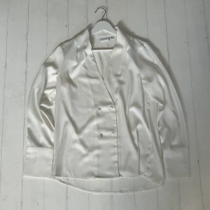 Vit omlottblus från Vila - Säljer nu denna vita skjorta/omlottblus i bra skick🙌. Insidan har en liten defekt (se bild tre). Perfekt nu i sommaren! 