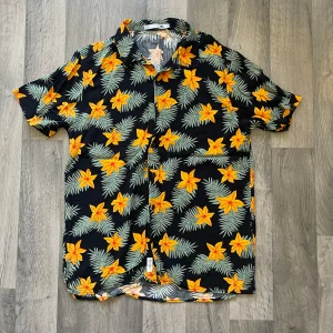 Lager 157 blommig kortärmad skjorta - Snygg kortärmad skjorta från Lager 157 i storlek M. Modellen är 167 cm lång, väger 63 kg. Längden är 77 cm, axeln är 47 cm.