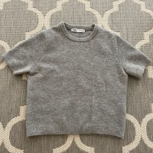 Grå stickad kortärmad tröja från Zara - Supermjuk grå stickad tröja från Zara med korta ärmar. Använd och tvättad. Använd ett flertal gånger men sedan inte mer. Finns ej att köpa på Zaras hemsida längre. 