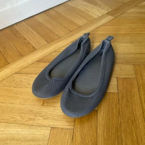 Mörkgrå ballerinaskor i textil - Står ingen storlek, skulle gissa 33/34 .Snygga och enkla mörkgrå ballerinaskor i textil med rund tå och platt sula.