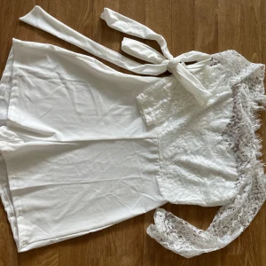 Vit spetsig playsuit med knytband - Superfin vit playsuit med spetsdetaljer och knytband i midjan