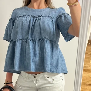 Blå volangblus i jeans material - Supersöt blå blus med volanger och lös passform. Perfekt ny till sommaren!! 