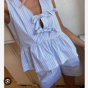 Blus eller topp från Neo Noir - Snygg topp/blus från Neo Noir i vitt och ljusblått  randigt mönster. Toppen har en relaxed passform som känns luftig och fräsch. Perfekta för varma sommardagar och matchas enkelt med underdelar. Använd en gång!