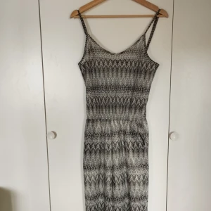 Luftig byxdress med lite glitter - Snygg byxdress med detaljerat svartvitt mönster som glittrar lite. Halv transparent men med täckning runt skrevet. Perfekt för dig som gillar boho-vibes eller disco och vill sticka ut med ett unikt mönster.