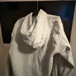 Ljusgrå oversized hoodie med huva - Enkel och stilren ljusgrå hoodie med huva och snörning. Tröjan har en klassisk känguruficka framtill och en oversized passform som ger en avslappnad vibe. Perfekt för chill dagar eller när du vill ha något bekvämt och snyggt.