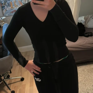 Svart v-ringad tröja i storlek 38 - En svart, tight och v-ringad tröja med lång ärm. Tröjan är ribbad nertill och vid ärmsluten, vilket ger en snygg passform. Perfekt att styla med jeans eller kjol för en clean look.