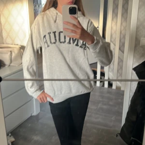 Ljusgrå hoodie med tryck - Säljer en ljusgrå hoodie med svart texttryck framtill. Tröjan har huva med snörning och en avslappnad passform. Perfekt för dig som gillar en enkel och stilren look. Mjuk och skön, passar till jeans eller leggings.