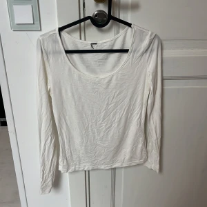 Vit långärmad topp med rund hals - En basic vit långärmad topp med rundad halsringning. Enkel och stilren design som passar till det mesta. Tillverkad i mjukt bomullsmaterial för en skön känsla hela dagen. Stretchig i materialet men skulle uppskatta storlek s!