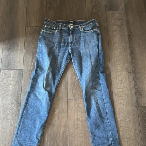 Blå jeans från Jack & Jones - Klassiska blå jeans från Jack & Jones med fem fickor och snygga kontrastsömmar. Jeansen har rak passform och normal midja, tillverkade i slitstarkt denim. Perfekta för en avslappnad och stilren look.