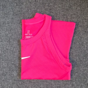 Nike träningslinne - Mörkrosa träningslinne ifrån Nike. Älskar denna färgen och linnet är i jättebra skick. Använd 2ggr💕Säljer en likadan i blå!💙 Köp båda för 150kr 🙌🏼