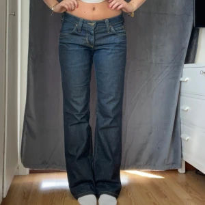 Mörkblå bootcut vintage jeans från Lee - Snygga mörkblå jeans från Lee med klassisk bootcut-passform och låg midja. Jeansen har kontrastsömmar och Lee-logga på bakfickan. Tillverkade i slitstarkt denim med en stilren look som passar till allt. Står att storleken är 30-31 men jag har 36 och de passar mig 