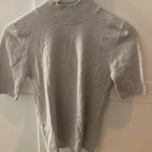 polotröja med kort ärm - En stilren  polotröja med korta ärmar och ribbad hög krage. Perfekt för lager-på-lager och funkar lika bra till jeans som kjol. Mjuk och skön känsla, enkel att matcha med andra plagg.