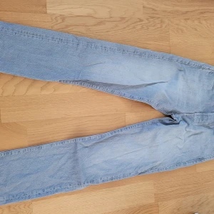 Ljusgrå jeans från Jack & Jones - Säljer ett par ljusgrå jeans från Jack & Jones i klassisk rak modell. Jeansen har fem fickor, knappgylf och snygga kontrastsömmar. Perfekt för dig som gillar en enkel och tidlös stil. Storlek 28/32.