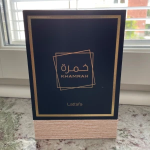 Lattafa Khamrah Eau de Parfum 100ml - Exklusiv parfym från Lattafa, Khamrah, i en lyxig mörkgrön och guld box. Flaskan är fyrkantig med elegant mönstrad glasdesign och guldiga detaljer. Innehåller 100 ml Eau de Parfum. Perfekt för dig som gillar unika och sofistikerade dofter. OBS! Locket sitter löst för nån anledning 