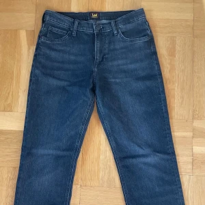 Svarta Lee ’West’ relaxed fit jeans - Använd endast en gång, noll tecken på användning.  Snygga Lee herrjeans med rak avslappnad passform och svart-grå stonewash, lite stretch. Köpt för 999kr på Carlings i Täby  Storlek 30/32  Säljer på grund av att de inte kommer till användning då jag tycker de är lite för långa för mig.   Material: 96% bomull 3% elastomultitester 1% elastan  Du ser på bild hur de passar på mig. Jag är 183 och bär normalt storlek 29/30 i midjan