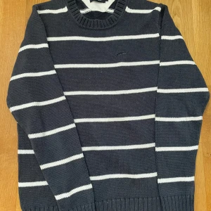 Randig stickad tröja  - Mörkblå stickad tröja från EastWest med vita  ränder. Klassisk rund halsringning med ribbade muddar vid ärmslut och nederkant. Perfekt för dig som gillar en stilren och tidlös look. Den är inte använd mycket och den är i fint skick. Hör av er vid frågor🫰