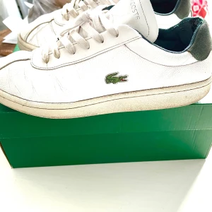 Vita sneakers från Lacoste i skinn - Snygga vita sneakers från Lacoste. Perfekt för en avslappnad men stilren look.Mindre skador,repor,slitage kan finnas.  Passar tjejer och killar. Ordpris:1299kr köpt på Zalando. Bildernas togs personligen av mig, vilket säkerställer att du ser exakt den produkt du köper.Vänligen observera att jag inte har någon öppetköp.