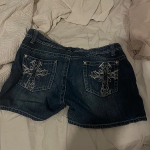 Jeansshorts med broderade kors - Skitsnygga shorts med coolt tryck på fickorna. Shortsen är väll använda men ändå i hyfsat skick💓💓