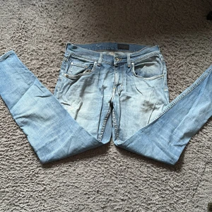 Ljusblå skinny jeans från Tiger of Sweden - Säljer ett par ljusblå skinny jeans från Tiger of Sweden. Klassisk femficksmodell med snygga detaljer och guldfärgade sömmar. Jeansen har normal passform och är tillverkade i mjukt denimtyg som sitter tajt längs benen.