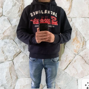 Mörkblå hoodie Jack & Jones Superior - Mörkblå hoodie från Jack & Jones med stor vit och röd Superior-logga på bröstet. Klassisk huva med snörning och mjuk insida. Perfekt för dig som gillar streetstyle och vill ha en bekväm och snygg tröja med tydlig branding. Sitter utmärkt skön o ha hemma o chilla i eller om du ska vara ute ! I princip helt oanvänd o nytt skick!kan självklart pruta vid snabb affär!!