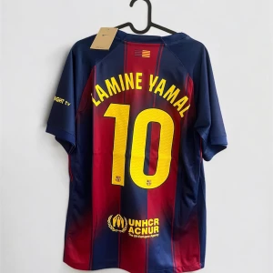 FC Barcelona Lamine Yamal tröja Nike - Säljer en FC Barcelona matchtröja med Lamine Yamal och nummer 10 på ryggen. Tröjan är randig i mörkblått och rött med gula detaljer, Spotify-logga och klubbmärke på bröstet. Tillverkad i lätt polyester, perfekt för dig som älskar Barca och vill ha en snygg och bekväm supportertröja.