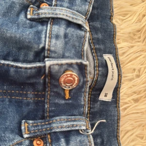 Blå Perfect Jeans från Gina Tricot - Snygga blå jeans från Gina Tricot, modell Perfect Jeans. Klassisk femficksdesign, normal passform och med snygga slitningar. Jeansen har medelhög midja och är tillverkade i mjukt denimtyg med stretch för extra komfort.