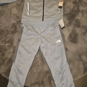 Grå/blå tracksuit från The North Face - Hösten är påväg 🍂🍁  North Face dress till salu, helt ny med lappar, material perfekt för höst/vinter. Dessutom slutsåld överallt och sällsynt modell och färg.  Byxor stlk M, men passar upp till 186 cm. Tröja stlk L. 🫡 