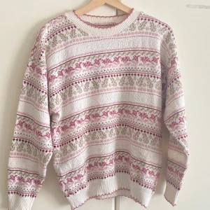 Mönstrad stickad tröja i rosa och vit - Säljer en mysig stickad tröja med klassiskt mönster i ljusrosa, lila och vitt. Tröjan har rund hals, ribbade muddar och långärmad passform. Perfekt för dig som gillar retrovibbar och vill ha något extra gulligt i garderoben.